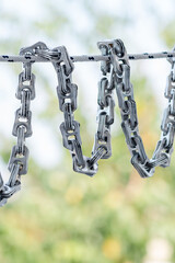 Creative chain made from aluminum can tabs on green nature background, a conceptual artwork...