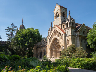 Obraz premium Stone chapel with arched portal and garden, ideal for illustrating religion, history, architecture, and cultural heritage concepts.