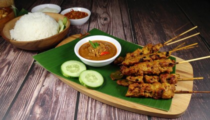 Savor delicious chicken satay skewers with creamy peanut sauce and fluffy rice, perfectly plated for a flavorful meal experience.