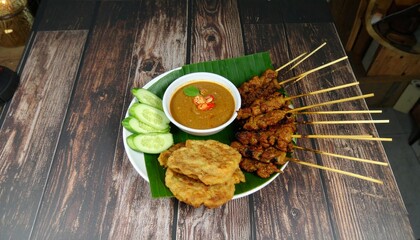 Savor Delicious Grilled Satay Skewers with Peanut Sauce, Cucumber Slices, and Fried Cakes