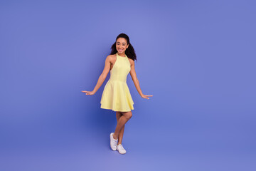 Young woman in a stylish yellow dress posing confidently against a vibrant purple background,...