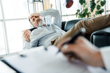 Mature man in therapy session experience emotional distress while discussing personal challenges...