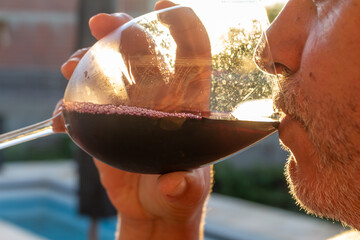 Man drinking red wine at sunset.