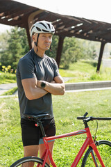Cyclist standing wearing gray t-shirt and relax at urban city park. Athlete taking a break. Outdoor...