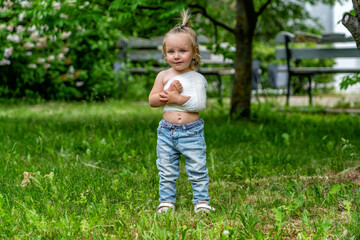 Young child with bandaged arm stands confidently in sunlit green park, showcasing resilience and...