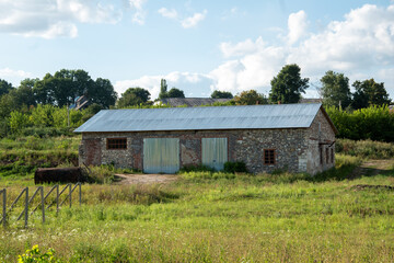 Fototapeta premium A small stone building with a metal roof in a field