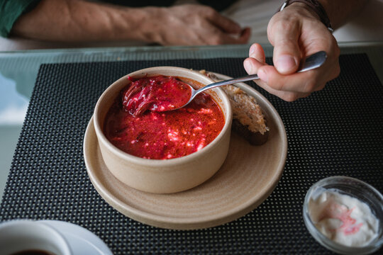 Close-up of a man sitting at a table eating a bowl of traditional borscht soup