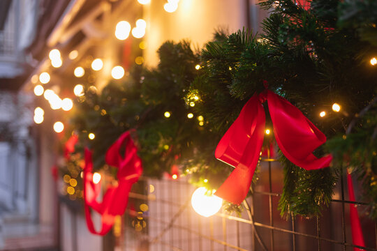 Christmas decorations made from fir branches, string lights and ribbons hanging outside a building
