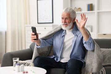 Senior man having online consultation with doctor via smartphone at home