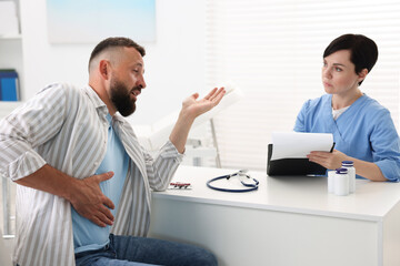 Obraz premium Gastroenterologist consulting patient with stomach pain in clinic