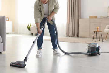 Man cleaning floor with vacuum cleaner at home, closeup