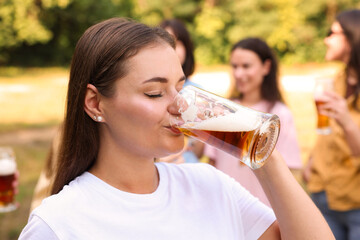 Group of happy friends having fun and drinking beer outdoors, selective focus