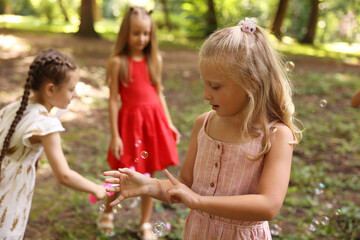 Cute little kids having fun with soap bubbles in park, selective focus
