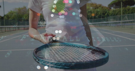 Standing tennis player holding racket at waist on blue court, chain-link fence and floating letters