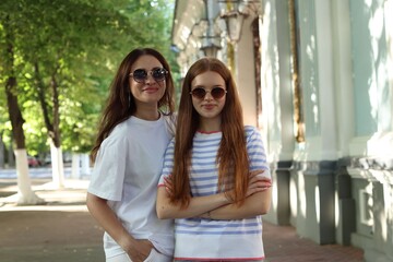 Portrait of beautiful mother and her teenage daughter in sunglasses on city street