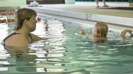 Swimming Instructor in Pool with Little Boy Giving Lessons