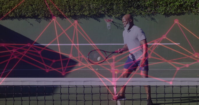 Swinging senior man playing tennis at backyard court with racket, ball, hoop, red network overlay