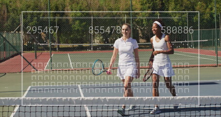 Walking women wearing tennis attire carrying tennis rackets across tennis court, with net and fence