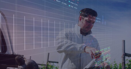 Pointing technician reviewing digital stock charts on tablet at outdoor industrial site, with valve