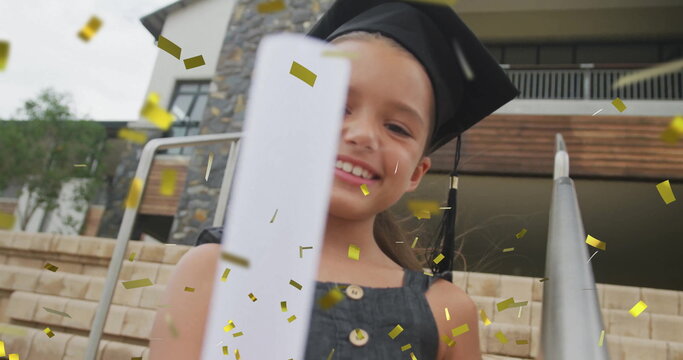 Smiling child wearing mortarboard cap and dress holding diploma on stone steps, with gold confetti - Powered by Adobe