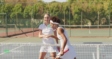Greeting match opponents shaking hands across tennis net at park court, with rackets headband lines