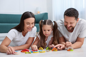 Parents and their daughter playing with toys on warm floor at home. Heating system