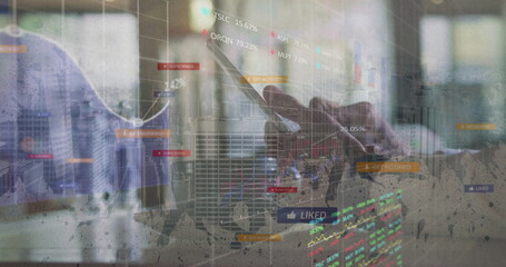 Tapping smartphone on laptop keys, dark shirted male analyzing floating charts at office desk