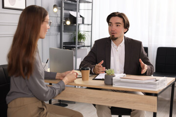 Coworkers discussing project together at desk in office