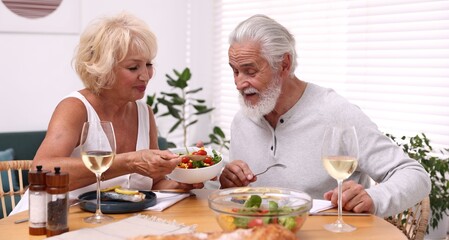 Elderly couple having dinner at table indoors