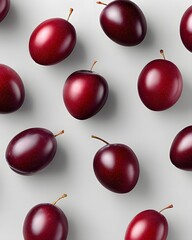 Scattered red plums isolated on light gray background, minimalistic fruit pattern top view