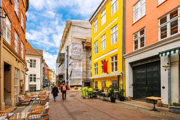 Colorful shops and sidewalk cafes along Kompagnistræde street in the historic center of Copenhagen, Denmark.