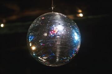 Classic silver disco ball hanging in a vibrant night club setting creating an enchanting atmosphere for dancing and celebrations