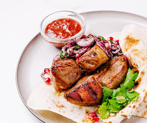 Delicious grilled meat with onions and tomato sauce on a white plate