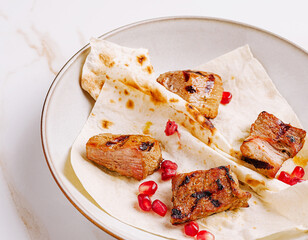 Grilled meat with pomegranate on flatbread served in a bowl