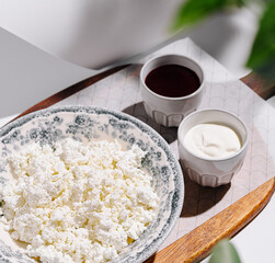 Delicious cottage cheese served with honey and sour cream on a wooden tray