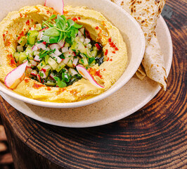Delicious hummus topped with fresh vegetables served with flatbread