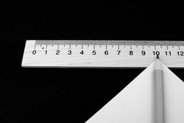 Pencil and wooden measuring ruler on black background