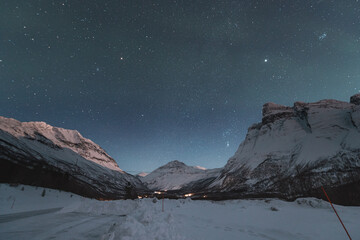 Dancing green and purple aurora borealis light up the starry sky over Norway majestic Lyngen Alps,...
