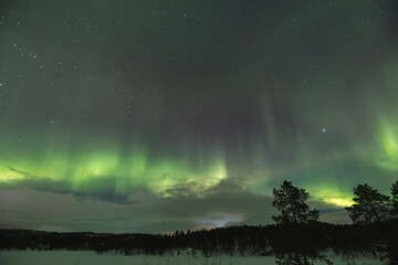 Northern lights light up the entire sky with their ever-changing shapes, painting it in vibrant...