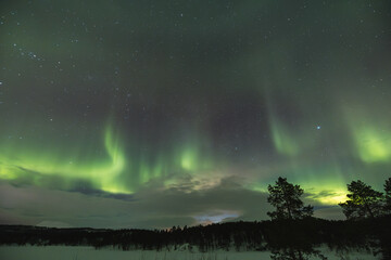 Northern lights light up the entire sky with their ever-changing shapes, painting it in vibrant...