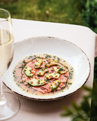 An Elegant Carpaccio, beautifully arranged with Fresh Garnish and paired