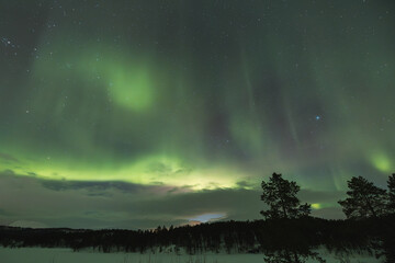 Northern lights light up the entire sky with their ever-changing shapes, painting it in vibrant...