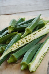 Several fresh okra pods on wooden surface, close-up.