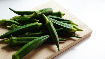Several fresh okra pods on wooden surface, close-up.