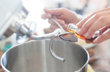 Preparing homemade Mucenici dough, a delightful Romanian tradition. Vanilla extract is carefully...