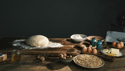 Dough sits ready on a wooden board, surrounded by ingredients for crafting Romanian Mucenici. A...