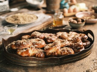 Golden brown Mucenici, topped with walnuts, fill an ornate wooden tray. Honey and baking...