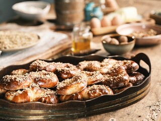 A rustic wooden tray overflows with golden-brown Mucenici, each glistening with a honey glaze and...