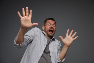 Man suffering from panic attack on grey background