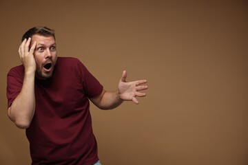 Man suffering from panic attack on brown background, space for text